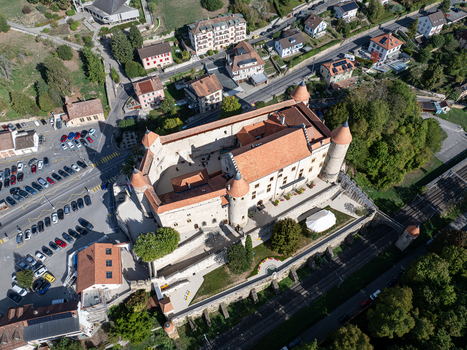 Aerial view of Chateau de Grandson a historic medieval castle with stone walls towers and terracotta roofs situated in the town of Grandson Vaud Switzerland.