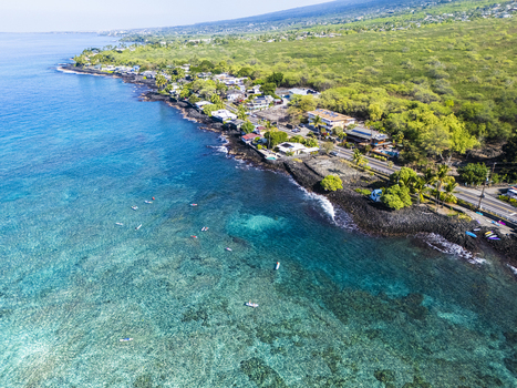 Aerial view of Kahalu u Beach Park featuring turquoise coral reefs volcanic rocky shoreline and lush coastal vegetation in Kailua Kona Hawaii United States. Aerial view of Kahalu u Beach Park featuring turquoise coral reefs volcanic rocky shoreline and lush coastal vegetation in Kailua Kona Hawaii United States.