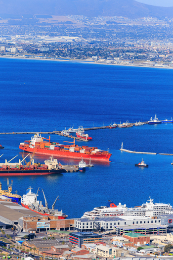 Aerial view of the bustling harbor with cargo ships contrasting against the deep blue ocean shadowed by the majestic Table Mountain Cape Town Western Cape South Africa.