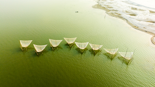 Aerial view of traditional fishing nets set up on bamboo structures in the calm river water near the sandy bank in Pabna Rajshahi Division Bangladesh.