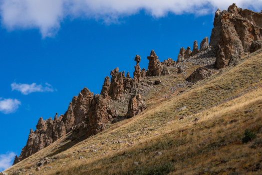 View of the rugged rock formations and jagged spires of San Luis Peak rising above the dry grassy slopes of the San Juan Mountains in Creede Colorado United States. View of the rugged rock formations and jagged spires of San Luis Peak rising above the dry grassy slopes of the San Juan Mountains in Creede Colorado United States.
