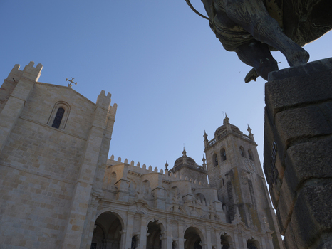View of the historic Porto Cathedral with its stone facade and towers under a clear blue sky featuring a statue in the foreground in Porto Porto District Portugal. View of the historic Porto Cathedral with its stone facade and towers under a clear blue sky featuring a statue in the foreground in Porto Porto District Portugal.