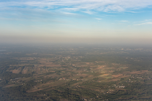 Aerial view of a sprawling landscape where patches of dark forest meet open fields under a hazy sky Warsaw Masovian Voivodeship Poland. Aerial view of a sprawling landscape where patches of dark forest meet open fields under a hazy sky Warsaw Masovian Voivodeship Poland.