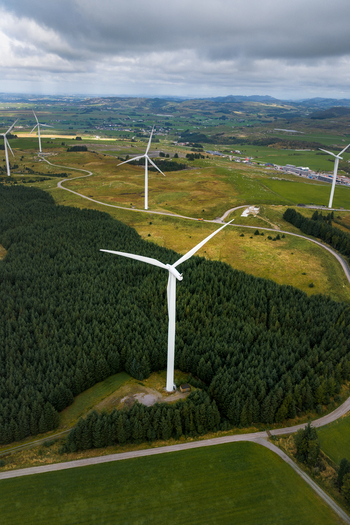 Aerial view of Hog Jaeren wind farm with large wind turbines rising above dense pine forests and rolling green hills in Ha Municipality Rogaland Norway. Aerial view of Hog Jaeren wind farm with large wind turbines rising above dense pine forests and rolling green hills in Ha Municipality Rogaland Norway.