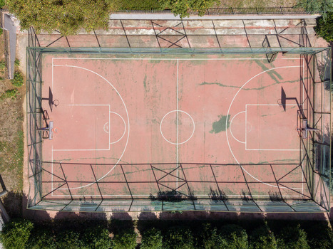 Aerial view of a red basketball court with white markings enclosed by a green chain link fence surrounded by trees in Istanbul Istanbul Turkiye. Aerial view of a red basketball court with white markings enclosed by a green chain link fence surrounded by trees in Istanbul Istanbul Turkiye.