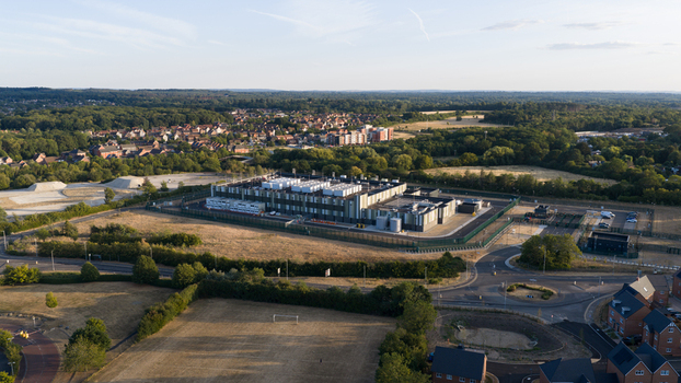 Aerial view of a modern data center facility surrounded by green fields trees and residential neighborhoods in Bracknell England United Kingdom.