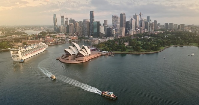 Aerial view of the Sydney Opera House situated on Bennelong Point with a cruise ship in the harbor surrounded by the modern city skyline and lush greenery in Sydney New South Wales Australia. Aerial view of the Sydney Opera House situated on Bennelong Point with a cruise ship in the harbor surrounded by the modern city skyline and lush greenery in Sydney New South Wales Australia.