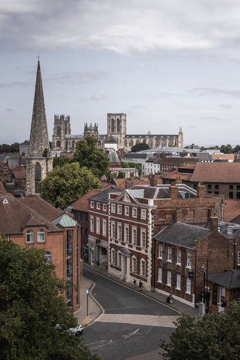 Aerial view of York Minster rising above the historic brick buildings narrow streets and lush trees of the city center in York England United Kingdom.