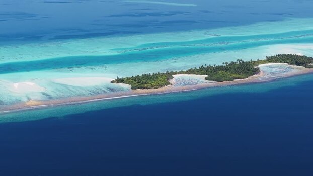 Aerial view of a tropical island and turquoise sea in Maldives.