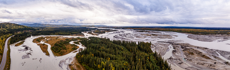 Aerial view of the Tanana River winding through the wilderness featuring braided channels dense coniferous forests and a highway in Yukon Koyukuk Census Area Alaska United States. Aerial view of the Tanana River winding through the wilderness featuring braided channels dense coniferous forests and a highway in Yukon Koyukuk Census Area Alaska United States.