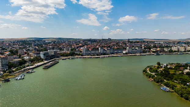 Aerial view of the city of Tulcea along the Danube river waterfront with boats docked urban buildings and lush greenery under a bright blue sky in Tulcea Tulcea Romania.