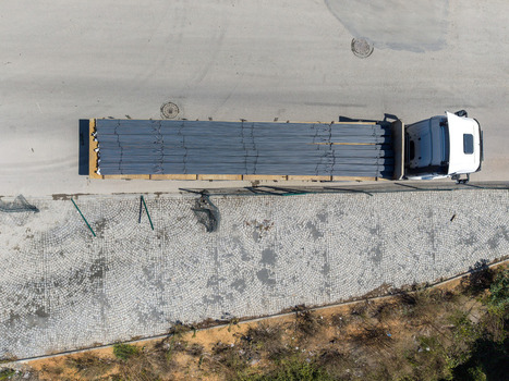 Aerial view of a white truck transporting a load of steel rebar on a paved road next to a cobblestone area in Istanbul Istanbul Turkiye. Aerial view of a white truck transporting a load of steel rebar on a paved road next to a cobblestone area in Istanbul Istanbul Turkiye.