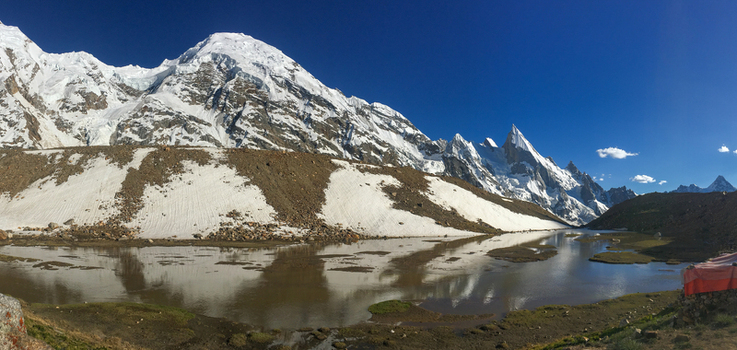 View of Laila Peak rising above a glacial lake with snow covered slopes rocky moraine and a clear blue sky in Gilgit Pakistan. View of Laila Peak rising above a glacial lake with snow covered slopes rocky moraine and a clear blue sky in Gilgit Pakistan.
