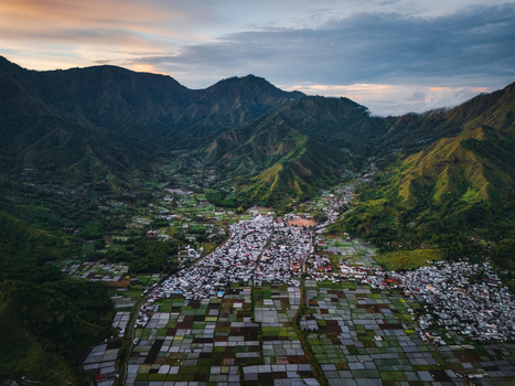 Aerial view of the Sembalun agricultural basin with its patchwork of rice fields and village houses nestled at the foothills of Mount Rinjani in Sembalun West Nusa Tenggara Indonesia. Aerial view of the Sembalun agricultural basin with its patchwork of rice fields and village houses nestled at the foothills of Mount Rinjani in Sembalun West Nusa Tenggara Indonesia.