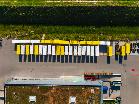Aerial view of Logistikzentrum Allhaming with rows of yellow and white shipping containers in a paved loading yard next to a warehouse with a green roof in Allhaming Oberosterreich Austria. Aerial view of Logistikzentrum Allhaming with rows of yellow and white shipping containers in a paved loading yard next to a warehouse with a green roof in Allhaming Oberosterreich Austria.