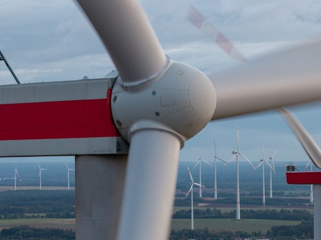Aerial view of Sieversdorf Windpark featuring a close up of a rotating wind turbine hub and blades with multiple turbines across the rural landscape in Jacobsdorf Brandenburg Germany. Aerial view of Sieversdorf Windpark featuring a close up of a rotating wind turbine hub and blades with multiple turbines across the rural landscape in Jacobsdorf Brandenburg Germany.