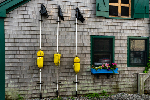 View of yellow fishing buoys on poles against a weathered cedar shingle wall at Martha s Vineyard in Edgartown Massachusetts United States.