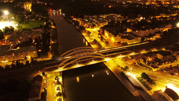 Aerial view of the illuminated bridge over the Oise River at night surrounded by the glowing streetlights and buildings of the town of Pontoise Ile de France France. Aerial view of the illuminated bridge over the Oise River at night surrounded by the glowing streetlights and buildings of the town of Pontoise Ile de France France.