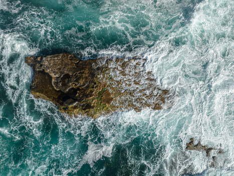 Aerial view of waves crashing against a large rock in the turquoise waters of La Jolla Cove San Diego California United States. Aerial view of waves crashing against a large rock in the turquoise waters of La Jolla Cove San Diego California United States.