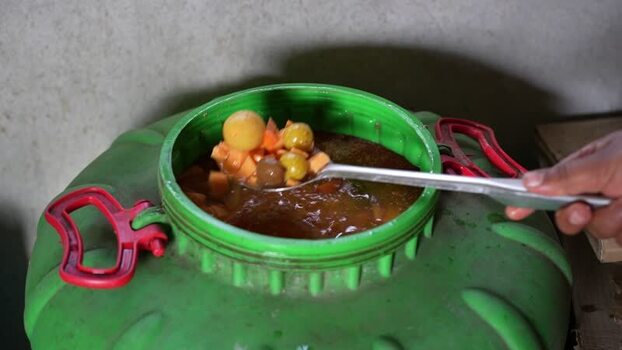 View of fermented fruit being scooped from a barrel Nepal.