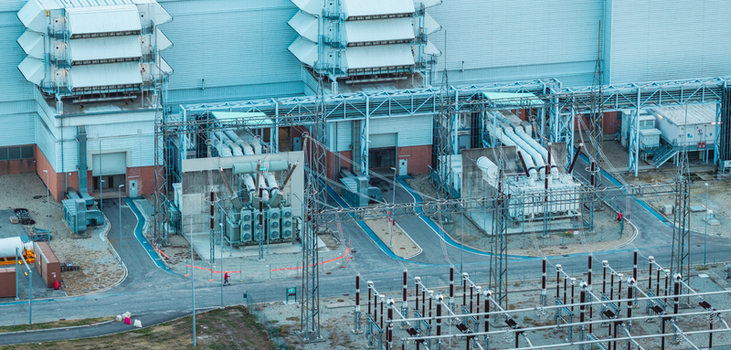 Aerial view of high voltage transformers switchgear and power lines at an industrial electrical substation in Italy.