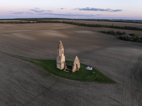Aerial view of the historic Pusztatorony ruins surrounded by vast agricultural fields at sunset with a small camper van parked nearby in Somogyvamos Hungary. Aerial view of the historic Pusztatorony ruins surrounded by vast agricultural fields at sunset with a small camper van parked nearby in Somogyvamos Hungary.