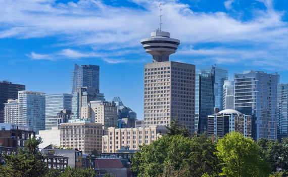 Aerial view of the Vancouver Lookout tower and downtown skyscrapers surrounded by lush green trees under a blue sky Vancouver British Columbia Canada.