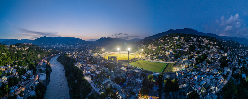 Aerial view of Muzaffarabad Cricket Stadium illuminated at dusk with the surrounding city lights river and mountain peaks in Muzaffarabad Azad Kashmir Pakistan. Aerial view of Muzaffarabad Cricket Stadium illuminated at dusk with the surrounding city lights river and mountain peaks in Muzaffarabad Azad Kashmir Pakistan.