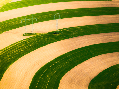 Aerial view of agricultural fields with alternating strips of green crops and brown soil and electricity pylons in Brno South Moravian Region Czechia.