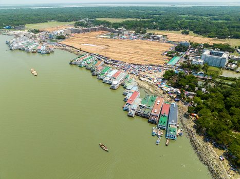 Aerial view of boats lining the muddy riverbank contrasting with the vibrant green trees and buildings Charmonai Barisal Division Bangladesh. Aerial view of boats lining the muddy riverbank contrasting with the vibrant green trees and buildings Charmonai Barisal Division Bangladesh.