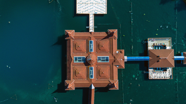 Aerial view of a distinctive building with a red tiled roof surrounded by the tranquil dark waters of Lake H&eacute;v&iacute;z Zala Hungary.