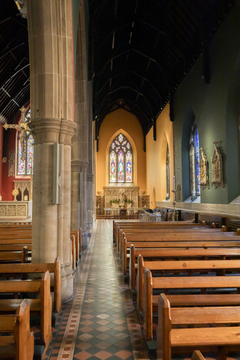 View of the interior of a historic church with wooden pews stone columns and stained glass windows in Newcastle upon Tyne England United Kingdom. View of the interior of a historic church with wooden pews stone columns and stained glass windows in Newcastle upon Tyne England United Kingdom.