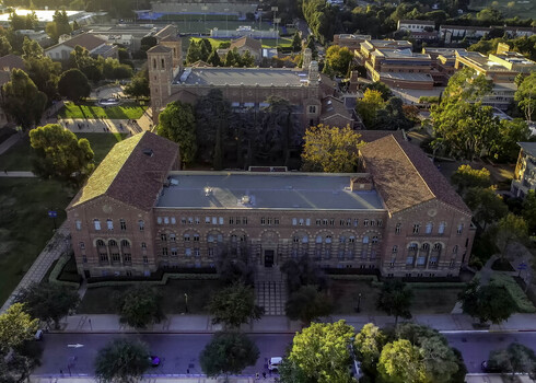 Aerial view of the historic Royce Hall at the UCLA Campus featuring its iconic twin towers red tiled roofs and surrounding lush greenery in Westwood California United States.