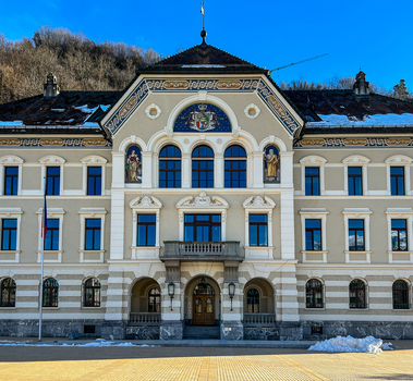 View of the historic Government Building with its ornate facade and central coat of arms under a clear blue sky in Vaduz Liechtenstein.