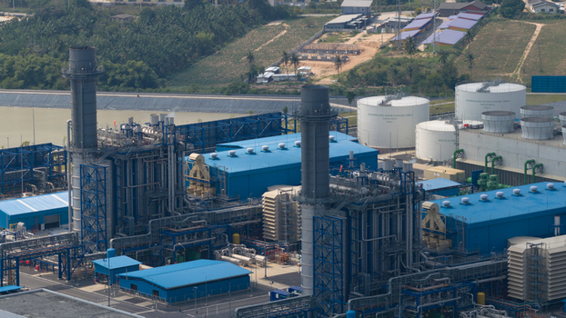 Aerial view of the Gulf PD Power Plant featuring tall chimneys blue industrial buildings and white storage tanks in Map Yang Phon Rayong Thailand.