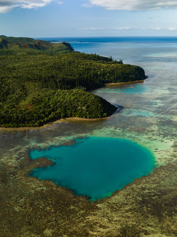 Aerial view of turquoise waters meet lush greenery a vibrant contrast against the backdrop of the clear blue ocean horizon Goro South Province New Caledonia. Aerial view of turquoise waters meet lush greenery a vibrant contrast against the backdrop of the clear blue ocean horizon Goro South Province New Caledonia.