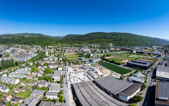 Aerial view of the Biel Bienne Boezingenfeld Champ industrial area with a construction site cranes and residential buildings under a clear blue sky Biel Bienne Canton of Bern Switzerland.