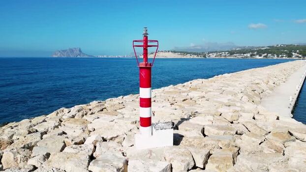 Aerial view of lighthouse on stone breakwater in Moraira Spain.