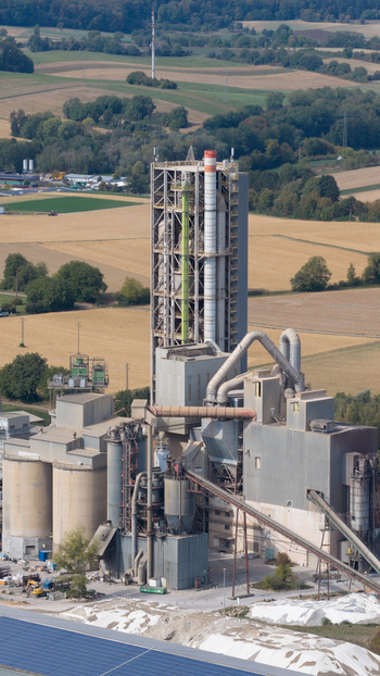 Aerial view of OPTERRA Wossingen GmbH cement plant with a tall industrial tower smokestacks and conveyor belts surrounded by agricultural fields in Walzbachtal Baden Wurttemberg Germany. Aerial view of OPTERRA Wossingen GmbH cement plant with a tall industrial tower smokestacks and conveyor belts surrounded by agricultural fields in Walzbachtal Baden Wurttemberg Germany.