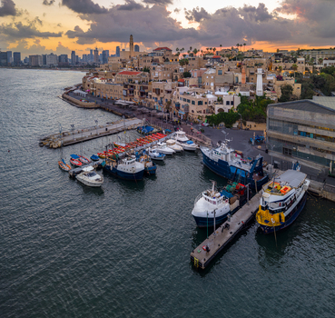 Aerial view of the historic Old port of Jaffa with fishing boats docked at the pier stone buildings and the Tel Aviv skyline in Tel Aviv Yafo Tel Aviv District Israel.