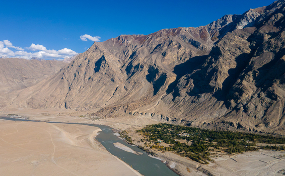 Aerial view of the Sarfaranga Cold Desert Shigar with a winding river rugged mountain slopes and a lush green oasis in Skardu Gilgit Pakistan.