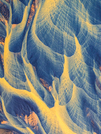Aerial view of intricate braided glacial river channels featuring contrasting blue water and yellow sediment deposits in Iceland. Aerial view of intricate braided glacial river channels featuring contrasting blue water and yellow sediment deposits in Iceland.