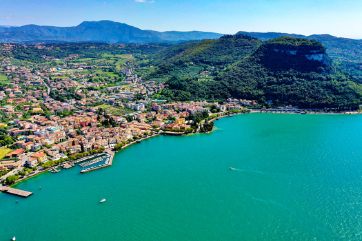 Aerial view of the town of Garda on the shores of Lake Garda with turquoise water lush green hills and a small harbor under a clear blue sky in Garda Veneto Italy. Aerial view of the town of Garda on the shores of Lake Garda with turquoise water lush green hills and a small harbor under a clear blue sky in Garda Veneto Italy.