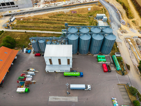 Aerial view of the Neuenstein Techno Zone featuring large metal grain silos industrial buildings and trucks parked in the paved yard in Neuenstein Baden Wurttemberg Germany. Aerial view of the Neuenstein Techno Zone featuring large metal grain silos industrial buildings and trucks parked in the paved yard in Neuenstein Baden Wurttemberg Germany.