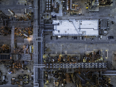 Aerial view of an oil refinery featuring complex piping systems industrial cooling fans and storage facilities at dusk Illinois United States.