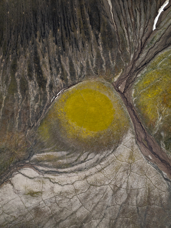 Aerial view of Krakatindur crater with vibrant yellow moss dark volcanic soil intricate drainage patterns and snow patches in the rugged landscape of Rangarthing ytra Iceland. Aerial view of Krakatindur crater with vibrant yellow moss dark volcanic soil intricate drainage patterns and snow patches in the rugged landscape of Rangarthing ytra Iceland.