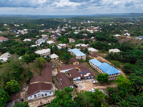 Aerial view of a vibrant settlement featuring prominent blue and white roofed buildings amidst lush green trees Asaga Abia Nigeria. Aerial view of a vibrant settlement featuring prominent blue and white roofed buildings amidst lush green trees Asaga Abia Nigeria.