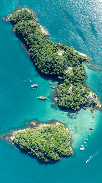 Aerial view of the Blue Lagoon surrounded by lush green islands and turquoise water with boats anchored in Angra dos Reis Rio de Janeiro Brazil.