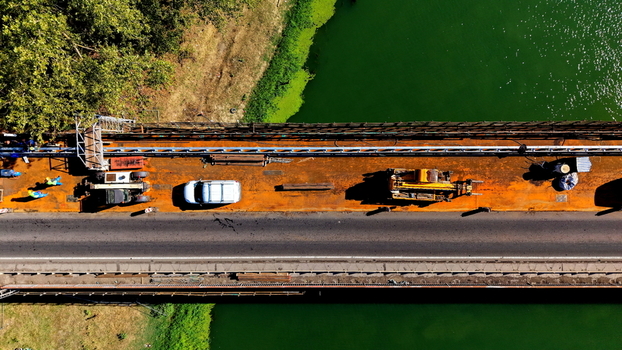 Aerial view of the Smederevo bridge and shipyard construction site with heavy machinery a vehicle and workers on the metal surface spanning the river in Smederevo Podunavlje District Serbia.