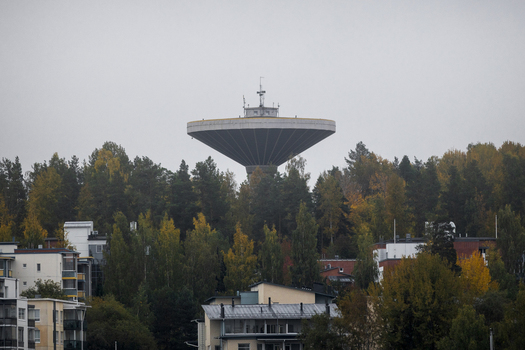View of the iconic water tower rising above a dense forest with autumn foliage and residential buildings in the foreground in Jyvaskyla Central Finland Finland.